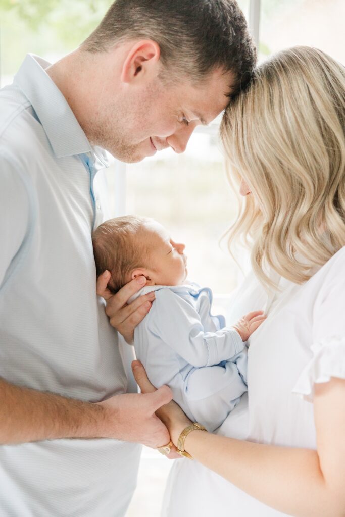 Cleveland newborn photographer parents holding newborn in front of window