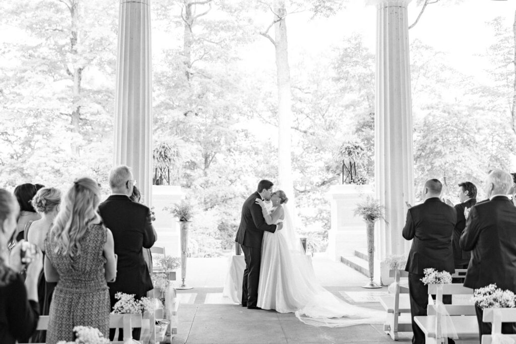 Hall of Philosophy Catholic wedding photographer in Cleveland captures ceremony Chautauqua Lake Bride and Groom sharing First Kiss
