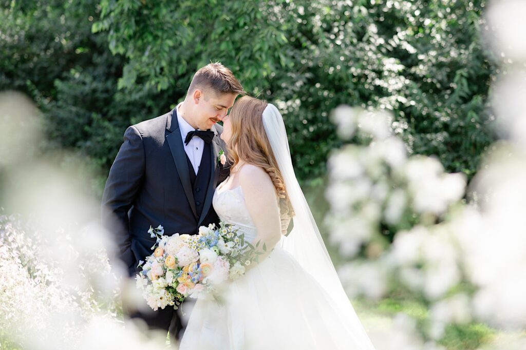 Akron wedding photographer Bride and Groom surrounded by flowers at St. Mary's Catholic Church in Hudson OH in summer with a wildflower bouquet